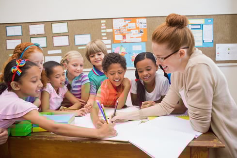 Teacher and pupils working at desk together at the elementary school-1 Teacher and pupils working at desk together at the elementary school-1
